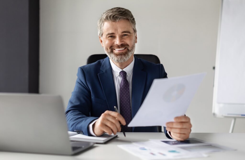 mature,businessman,in,suit,working,with,documents,at,desk,in